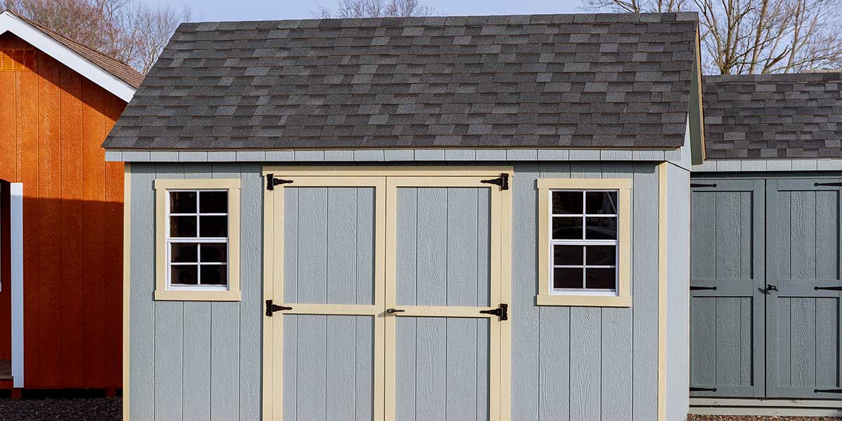 A modern light blue backyard shed structure with double doors, illustrating options when choosing between attached and detached ADUs.